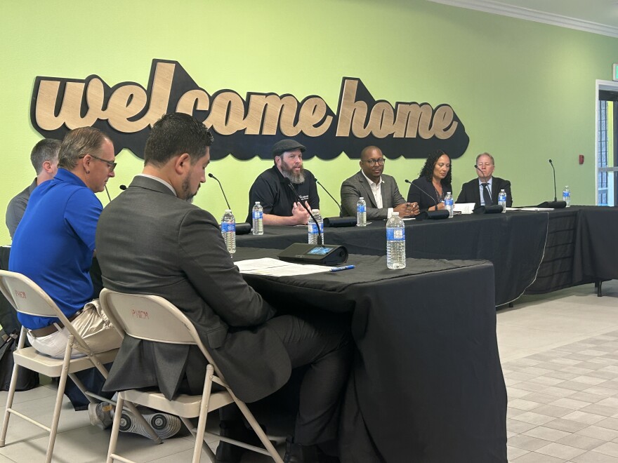 People sitting around tables in front of a graphic that says 'welcome home.'