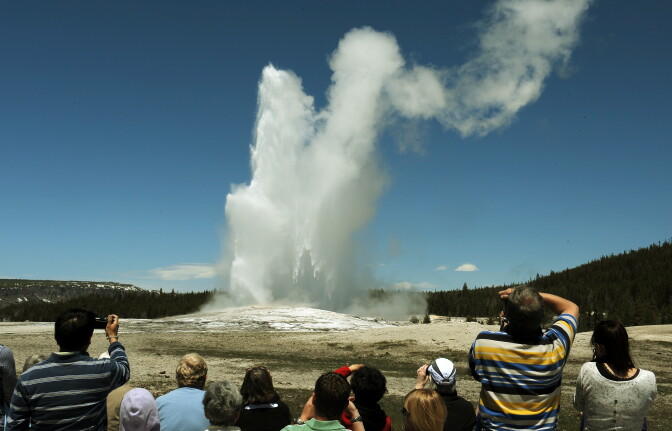 Tourists watch the 'Old Faithful' geyser which erupts on average every 90 minutes in the Yellowstone National Park, Wyoming on June 1, 2011.  Yellowstone National Park, was established by the U.S. Congress and signed into law by President Grant on March 1, 1872. The park is located primarily in the U.S. state of Wyoming, though it also extends into Montana and Idaho and was the first national park in the world. It is known for its wildlife and its many geothermal features, especially the Old Faithful Geyser.    
