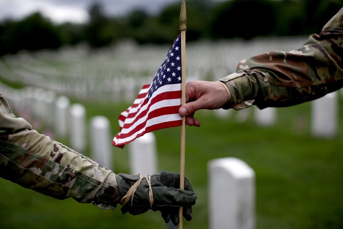 Sgt. Iwona Kosmaczewska (left) and Pvt. 2 Wesley Defee (right), members of the 3rd U.S. Infantry Regiment, place flags at the headstones of U.S. military personnel buried at Arlington National Cemetery, in preparation for Memorial Day May 25, 2017 in Arlington, Virginia.