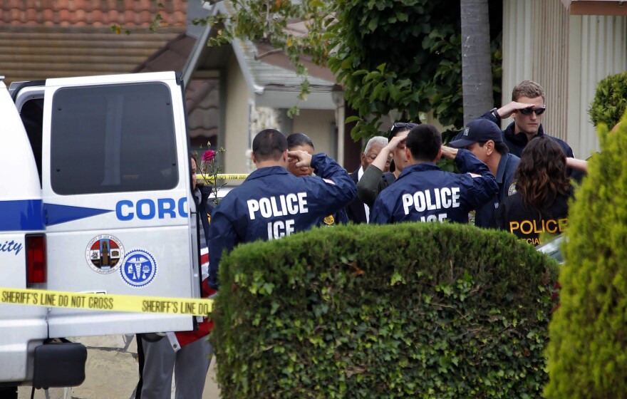 Immigration and Customs Enforcement agents lining the driveway of a home in Carson salute as the body of an ICE agent Myron Chisem, who was covered by an American flag as his body was wheeled to a coroner's van on Thursday. His14-year-old son was arrested Thursday morning on suspicion of murder.
