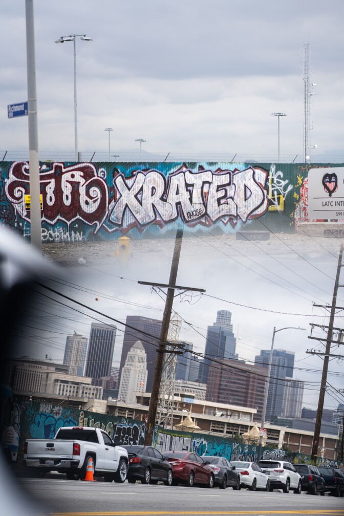 A photo capture of two blended pictures of graffiti and the downtown Los Angeles skyline. 