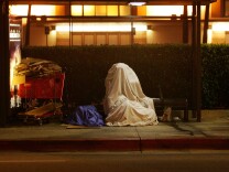A homeless person covers up on a bus stop bench before dawn October 12, 2007 in downtown Los Angeles, California.  Los Angeles city officials recently settled a 2003 lawsuit brought by advocates for homeless skid row residents who complained of being arrested for sleeping on sidewalks, despite having nowhere else to go. Under the new deal, people can sleep on Los Angeles sidewalks between 9 p.m. to 6 a.m. as long as they do not block doorways or driveways, or completely block the sidewalk. Los Angeles is often referred to as the homeless capital of the nation because of its estimated 40,144 people living on city streets and 73,000 homeless spread across the county, according to recent figures attributed to the Los Angeles Homeless Services Authority, The 73,000 homeless include 10,000 minors, 24,505 people suffering from a mental illness, 8,453 military veterans, and nearly 7,200 victims of domestic abuse. 