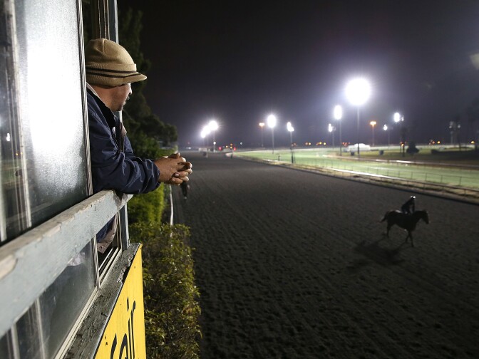 INGLEWOOD, CA - DECEMBER 21:  A track worker watches a horse run along the backstretch during morning workouts at Betfair Hollywood Park on December 21, 2013 in Inglewood, California.  The historic Betfair Hollywood Park race track is shutting its doors after 75 years of thoroughbred horse racing with the final race running on December 22. The 260 acre plot of land is scheduled to be turned into a new retail and housing development.  (Photo by Justin Sullivan/Getty Images)