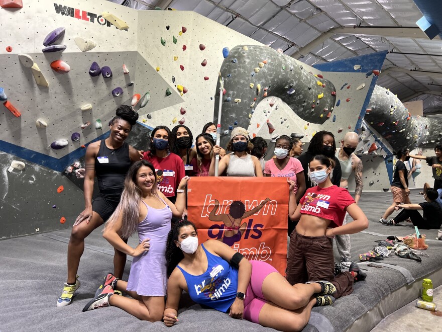 A picture of a group of women with a sign that says "Brown Girls Climb" at a rock climbing gym in Los Angeles, CA.