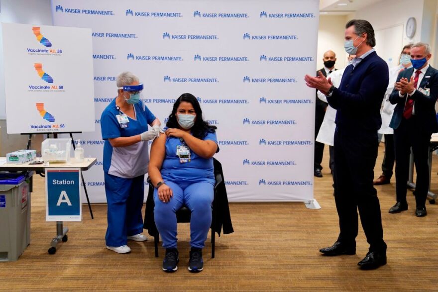 Governor Gavin Newsom looks on, far right, as ICU nurse Helen Cordova receives the Pfizer-BioNTech COVID-19 vaccine at Kaiser Permanente Los Angeles Medical Center in Los Angeles, California on December 14, 2020. - The United States kicked off a mass vaccination drive Monday hoping to turn the tide on the world's biggest coronavirus outbreak, as the country's death toll neared a staggering 300,000. (Photo by Jae Hong / POOL / AFP) (Photo by JAE HONG/POOL/AFP via Getty Images)