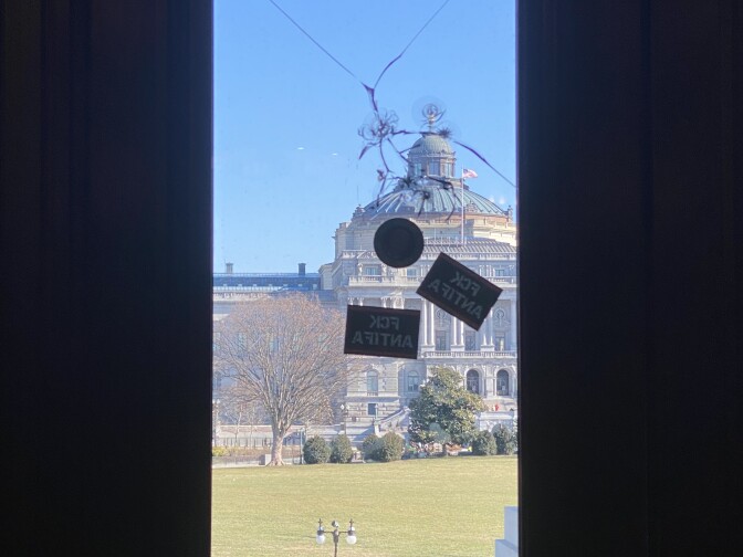 A window that's cracked in the upper middle with three stickers below it. 