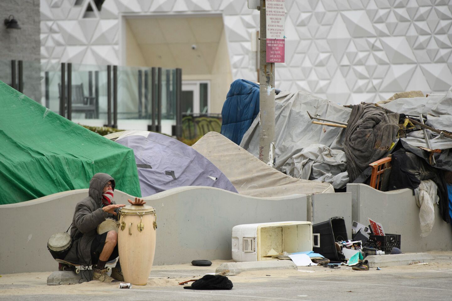 A person plays a musical instrument near an encampment at Venice Beach.