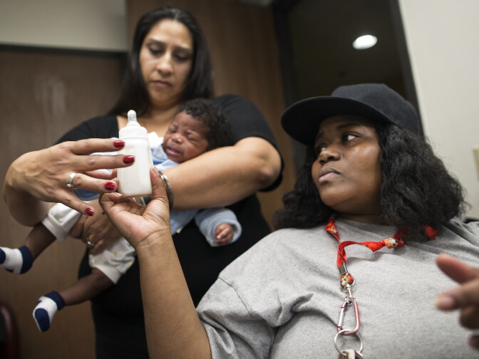 Mother Tamika Rosser hands a bottle to Health Educator Cecie Trujillo for 2-month-old Tray'von Lynn. Great Beginnings for Black Babies also provides child care during the class.