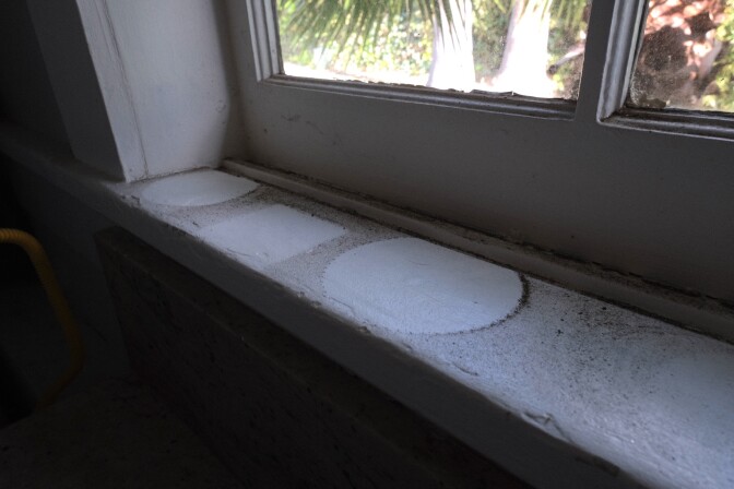 A dark layer of ash from the Eaton Fire is visible on a windowsill that held potted plants. Health officials have said this ash potentially contains lead, asbestos and arsenic. 