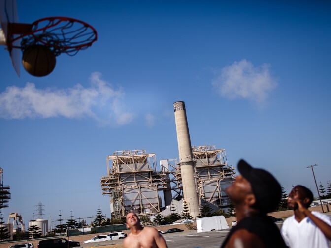 Huntington Beach locals play basketball across the street from the AES operated power plant.
