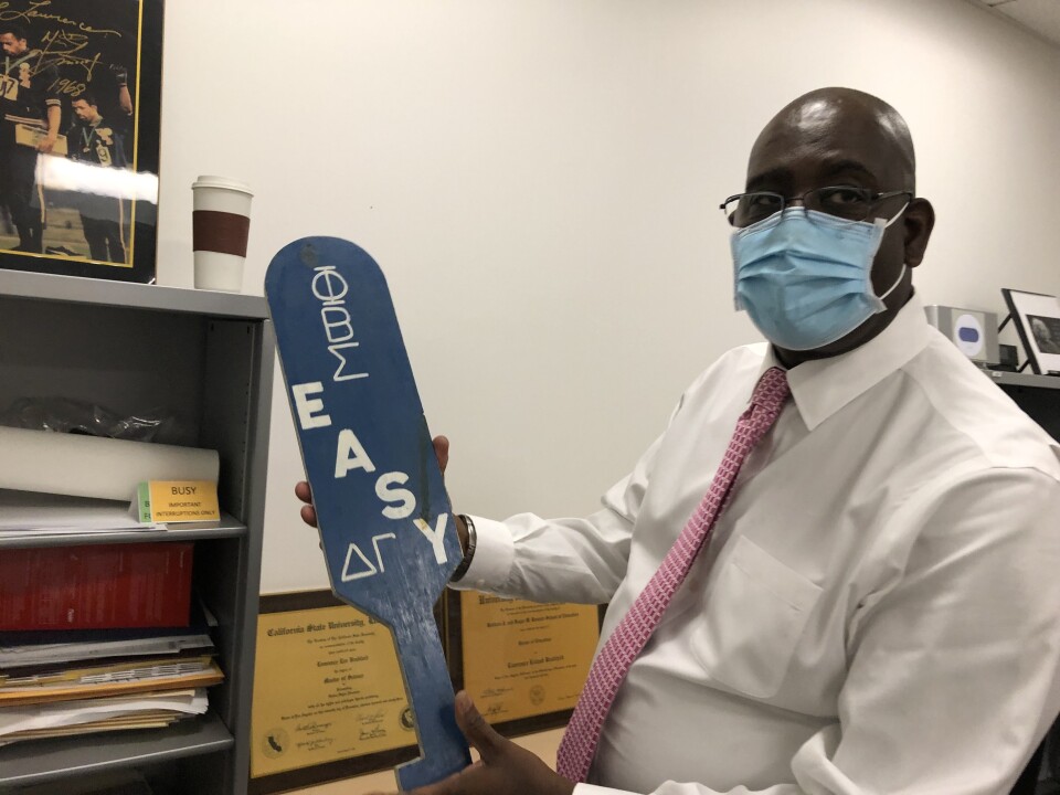 College administrator Lawrence Bradford holds a wood paddle from his college fraternity Phi Beta Sigma