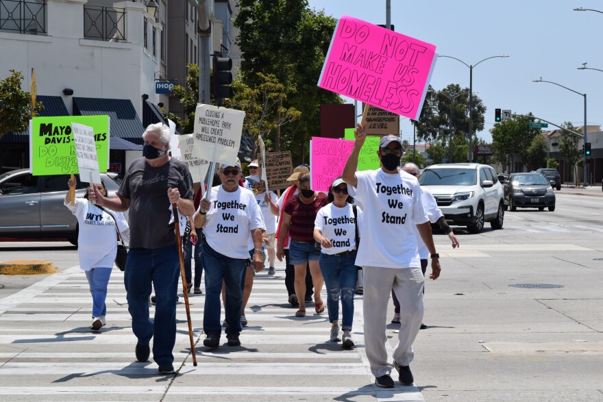 Protesters wearing T-shirts that read "Together We Stand" and carrying homemade signs cross the street in Carson.