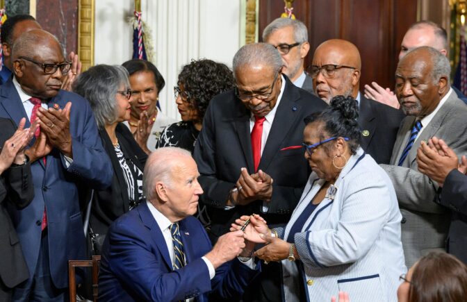 US President Joe Biden hands a pen to Till family member Dr. Marvel Parker, Executive Director of the Emmett Till & Mamie Till-Mobley Institute, after signing a proclamation establishing the Emmett Till and Mamie Till-Mobley National Monument in Illinois and Mississippi.