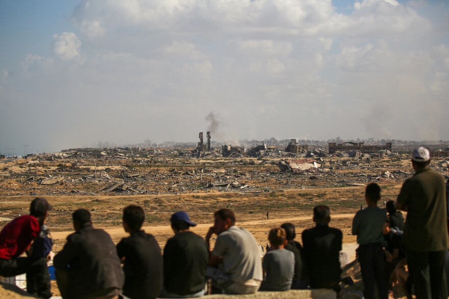 People are in a row looking toward a city in ruins.