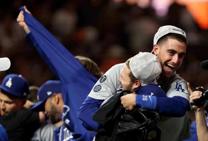 Dodgers players celebrate with one man hugging another in jubilation.