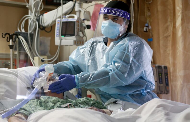 APPLE VALLEY, CALIFORNIA - DECEMBER 23:  (EDITORIAL USE ONLY) A clinician cares for a COVID-19 patient in the Intensive Care Unit (ICU) at Providence St. Mary Medical Center amid a surge in COVID-19 patients in Southern California on December 23, 2020 in Apple Valley, California. The 213 bed capacity hospital in San Bernardino County is currently treating at least 140 COVID 19-positive inpatients while operating at approximately 250 percent of ICU capacity. Southern California remains at zero percent of its ICU (Intensive Care Unit) bed capacity amid the spike in coronavirus cases and hospitalizations. (Photo by Mario Tama/Getty Images)