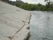 The Los Angeles River flows through the Frogtown neighborhood in Los Angeles, California. The river's banks are mostly concrete. 
