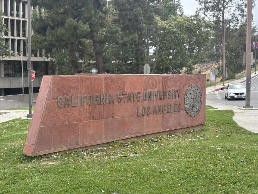 A stone sign at the entrance of Cal State University Los Angeles is set on grass. 