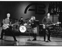 Black and white photo of four musicians playing on stage at American Bandstand.