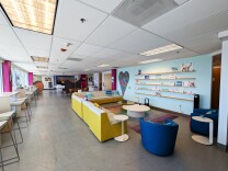 The interior of the allcove Beach Cities mental health center in Redondo Beach. There is a light blue wall surrounded by couches, chairs and tables. 