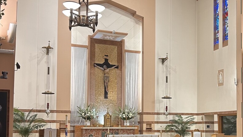 The interior of a church, with Jesus on a cross hanging from the tan and white walls.
