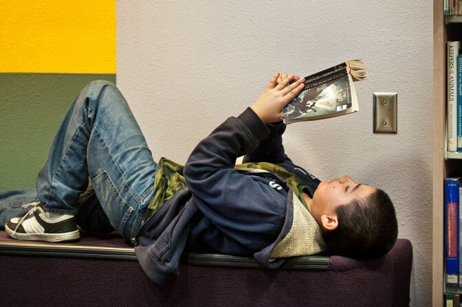 Anthony Garcia lays back and reads a book at the Junipero Serra Library.