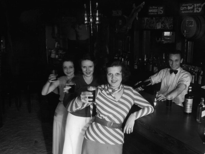 Female patrons at the Malamute Saloon, which was reportedly the first bar to open in Los Angeles after the 1933 repeal of Prohibition. The bar was designed to look like the log cabin Malamute Saloon near Fairbanks, Alaska, made famous in a poem by Robert W. Service. The L.A. version of the saloon featured a log cabin attached to a giant bottle. Circa 1933.