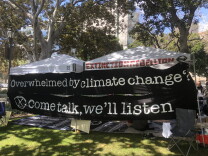  A black sign with white lettering reads "Overwhelmed by climate change? Come talk, we'll listen." 