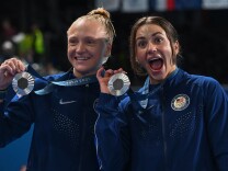 Two women hold silver medals 
