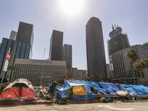 Tents used by the homeless line a downtown Los Angeles street with the skyline behind Tuesday, Sept. 22, 2015.