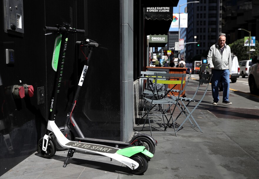 Bird and Lime scooters sit parked in front of a building on April 17, 2018 in San Francisco.