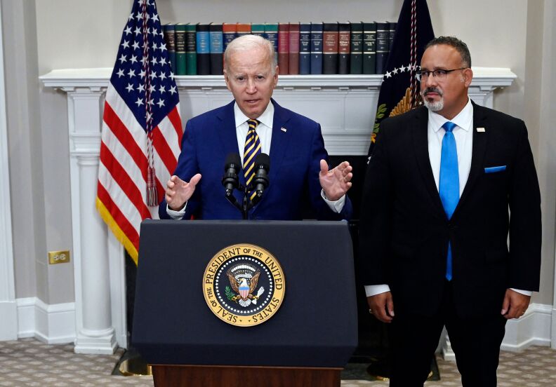 US President Joe Biden at a podium announcing student loan relief with Education Secretary Miguel Cardona to his left.