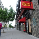 A woman walks by a damaged Wells Fargo branch in downtown Oakland, California on May 02, 2015. Hundreds marched throughout the city on May 1 to mark International Workers' Day vandalizing store fronts, smashing windows and lighting a car on fire before eventually dispersing.    AFP PHOTO/JOSH EDELSON        (Photo credit should read Josh Edelson/AFP/Getty Images)
