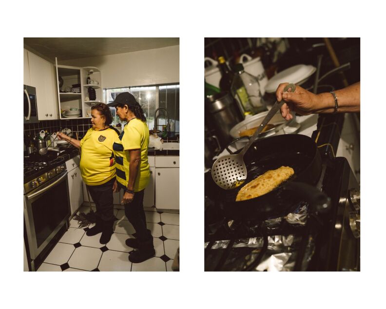 Two women in yellow soccer jerseys are in a kitchen cooking empanadas on a stovetop.