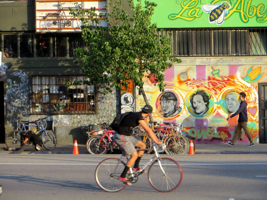 A cyclist passes community bicycle repair shop, The Bike Oven in Highland Park, Los Angeles.