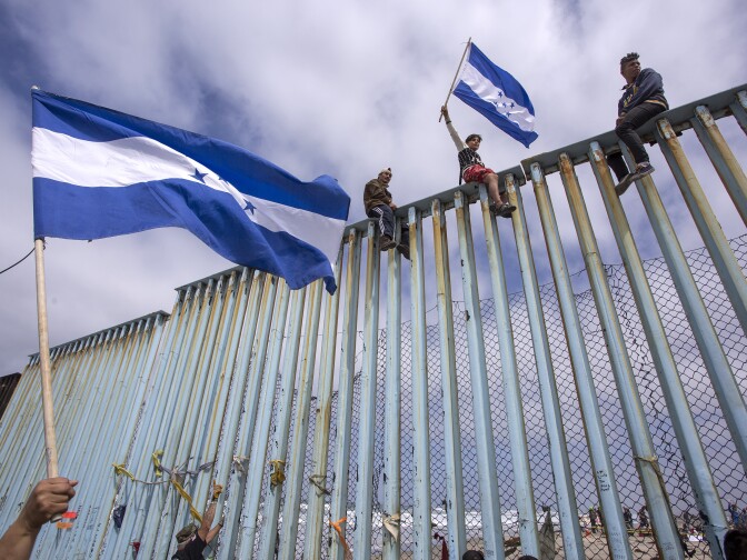 TIJUANA, MEXICO - APRIL 29: People hold Honduran flags at the border fence during a rally with members of a caravan of Central American asylum seekers and supporters on April 29, 2018 in Tijuana, Baja California Norte, Mexico. More than 300 immigrants, the remnants of a caravan of Central Americans that journeyed across Mexico to ask for asylum in the United States, have reached the border to apply for legal entry.   (Photo by David McNew/Getty Images)