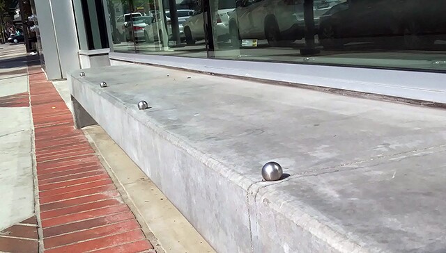A concrete ledge with silver spheres attached and spread out across the top.
