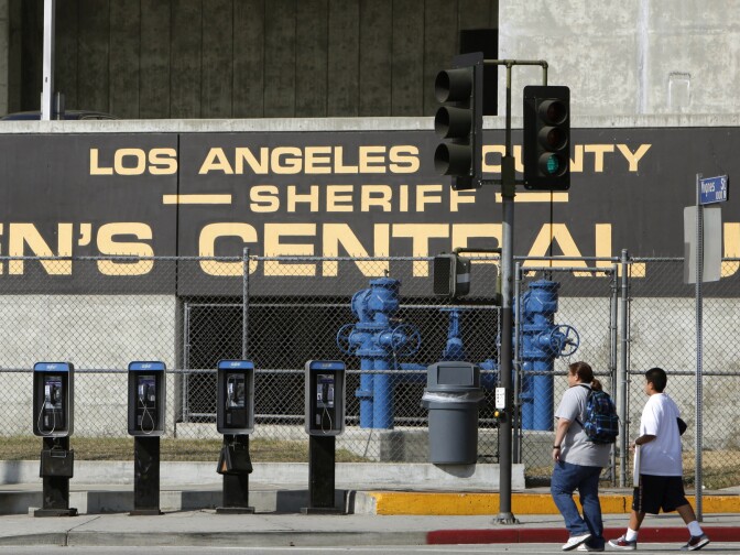 FILE - In this Sept. 28, 2011 photo, people walk past the Los Angeles County Sheriff's Men's Central Jail facility in Los Angeles. A federal judge has given initial approval to an agreement that requires the Los Angeles County Sheriff’s Department to improve conditions in its jails for inmates using wheelchairs and others with mobility impairments. (AP Photo/Damian Dovarganes, File)
