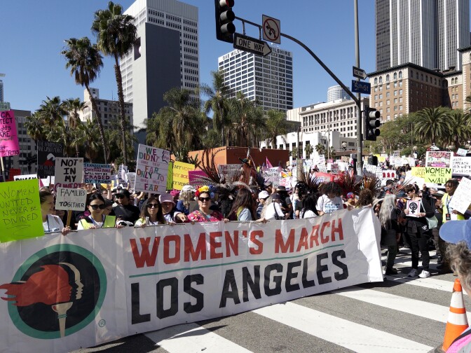 Groups of people standing behind a big banner that says, "Women's March Los Angeles."