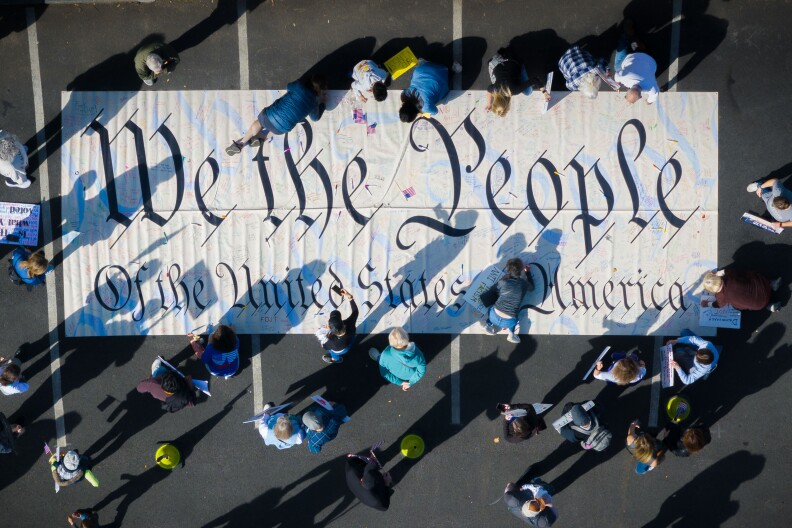 An overview of a sign being carried that reads: "We the People."