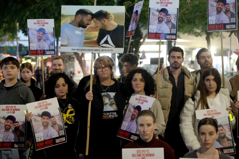 A group of people hold posters of hostages, some in their hands and some on tall sticks.