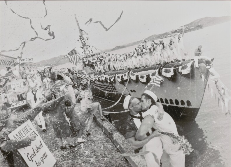 A black and white photo of two sailors kissing in front a ship amid a celebration.