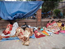 Nepalese residents rest as they gather on a pavement in Kathmandu on April 26, 2015, a day after an earthquake hit.