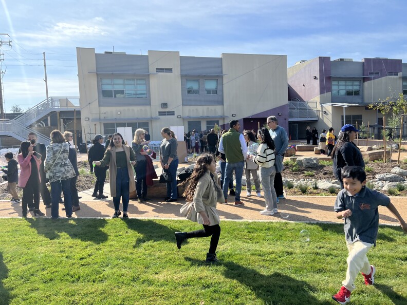 Many kids play on the grass of their new schoolyard.