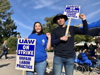 A man and a woman both hold their fists up during a workers strike at UC Irvine