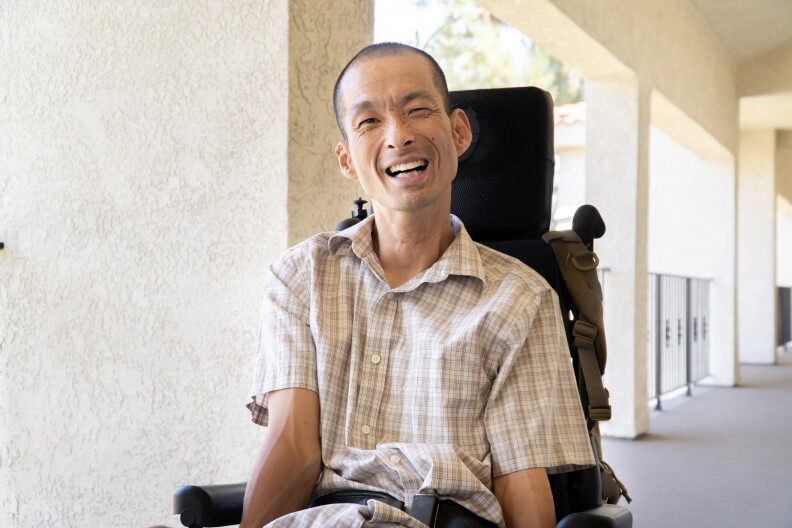 Tim Jin smiling at the camera in front of his Orange County apartment.