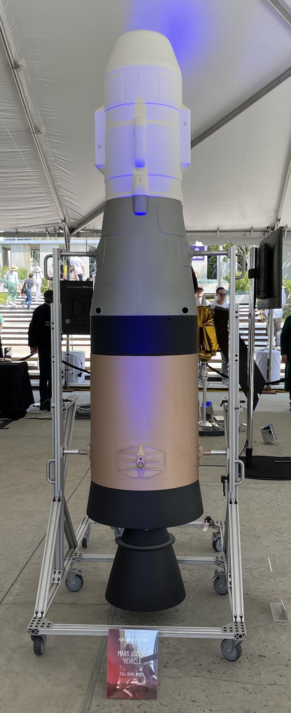 A ten foot tall missile looking device in the middle of an outdoor tent.