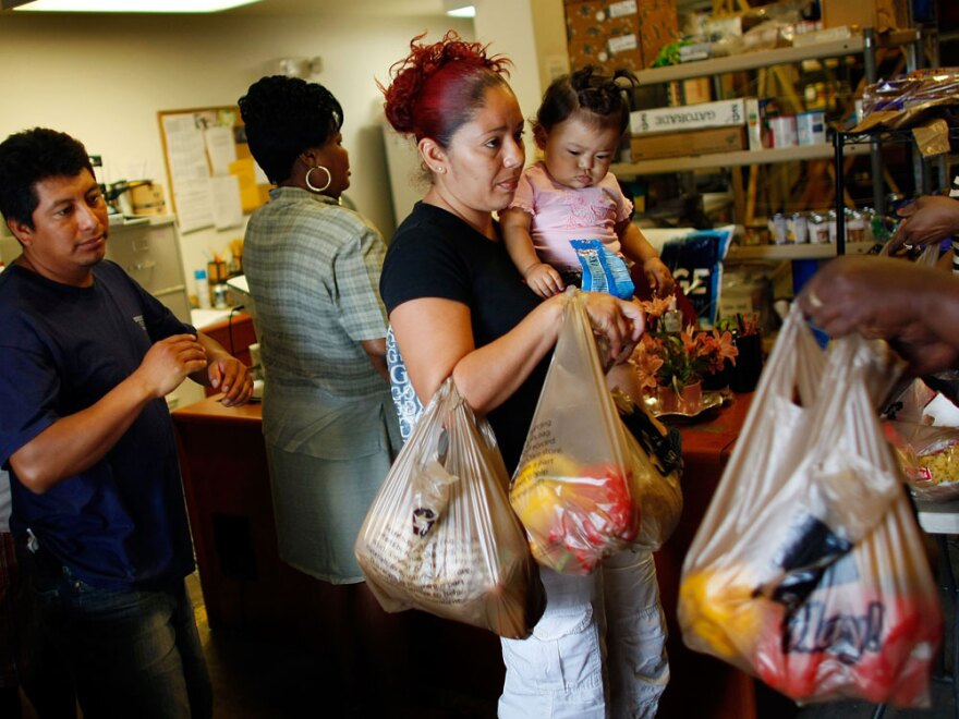 Abran Lopez (left), who was laid off from his job as a landscaper, and Angelina Martinez, who lost her construction job, receive groceries from a food co-op in Fort Lauderdale, Fla., in April 2009.