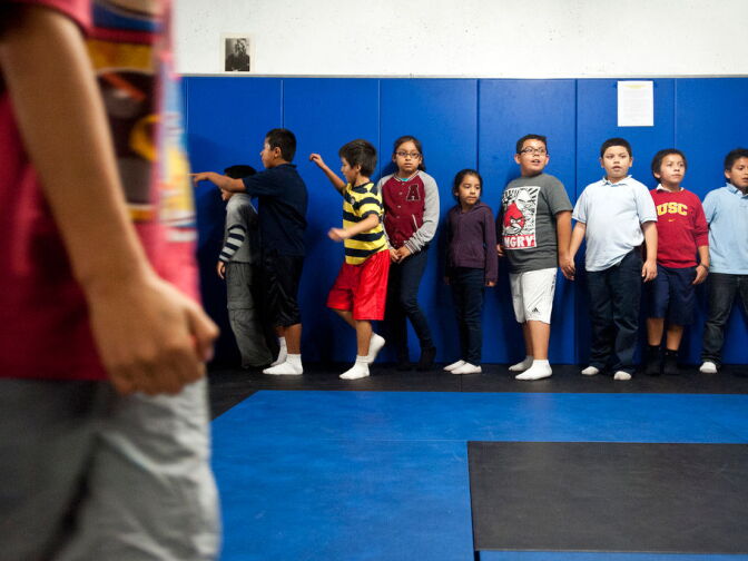 Kids spread out on a mat before doing stretches at the start of a CrossFit Tuesdays class. The PAL program also has events throughout the year. Before Christmas, officers will take kids to Pershing Square for ice skating, all free of charge.