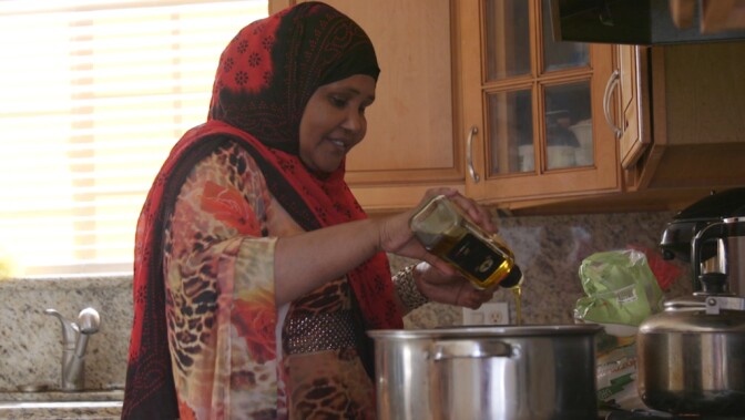 Mariam Ali, a Somali refugee who lives in San Diego's Teralta neighborhood, pours olive oil into a pot for alfredo sauce, Feb. 26, 2016.